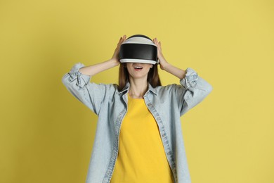 Photo of Woman using virtual reality headset on yellow background