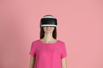 Photo of Smiling woman using virtual reality headset on pink background