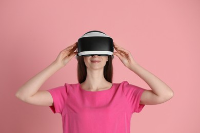Woman using virtual reality headset on pink background