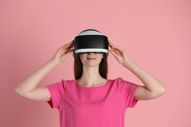 Photo of Woman using virtual reality headset on pink background