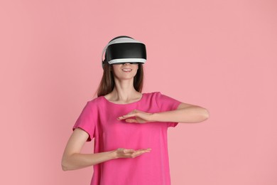 Photo of Smiling woman using virtual reality headset on pink background