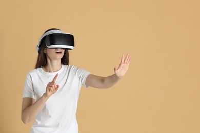 Photo of Woman using virtual reality headset on beige background, space for text