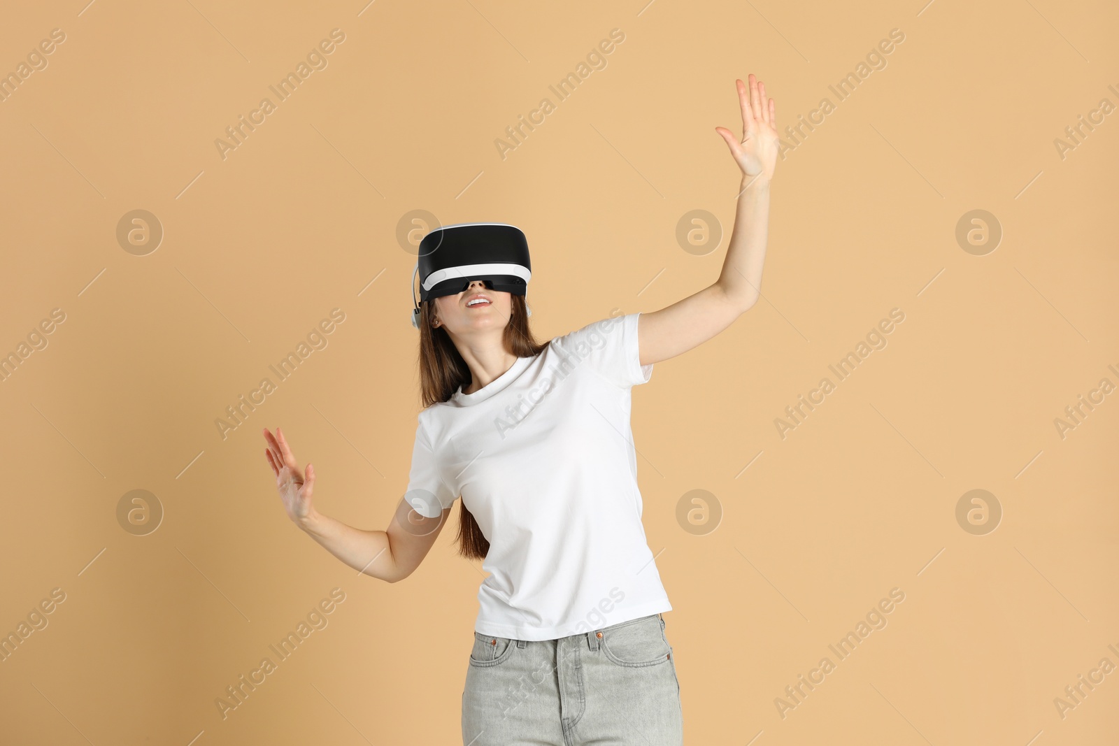Photo of Woman using virtual reality headset on beige background