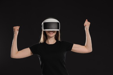 Photo of Smiling woman using virtual reality headset on black background