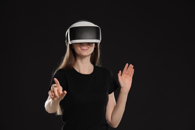 Smiling woman using virtual reality headset on black background