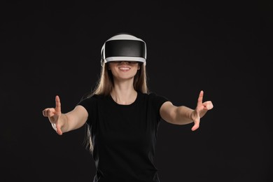Photo of Smiling woman using virtual reality headset on black background