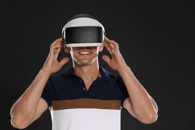 Smiling man using virtual reality headset on black background