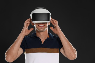 Photo of Smiling man using virtual reality headset on black background