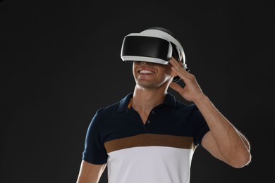 Smiling man using virtual reality headset on black background