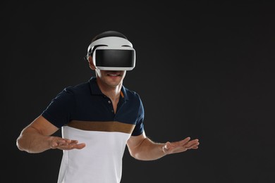 Man using virtual reality headset on black background, space for text
