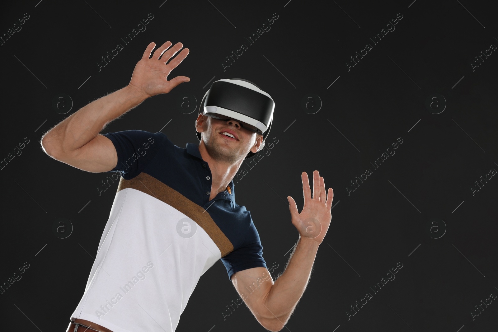 Photo of Smiling man using virtual reality headset on black background, space for text