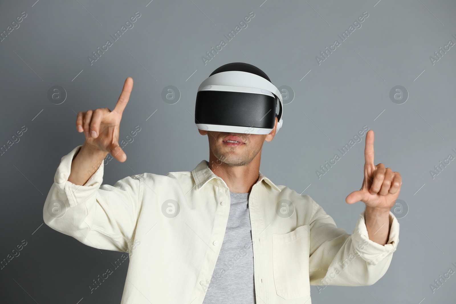 Photo of Man using virtual reality headset on gray background