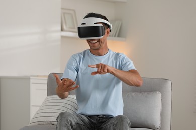 Photo of Smiling man using virtual reality headset at home