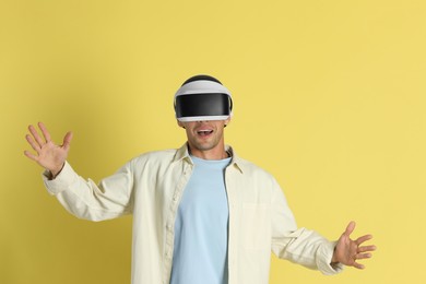 Photo of Emotional man using virtual reality headset on yellow background