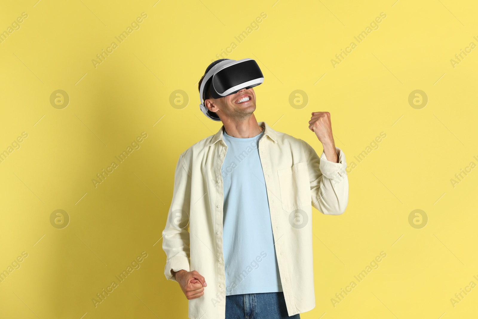 Photo of Smiling man using virtual reality headset on yellow background