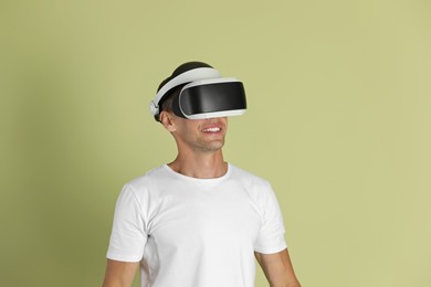 Photo of Smiling man using virtual reality headset on light green background