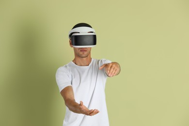 Photo of Man using virtual reality headset on light green background