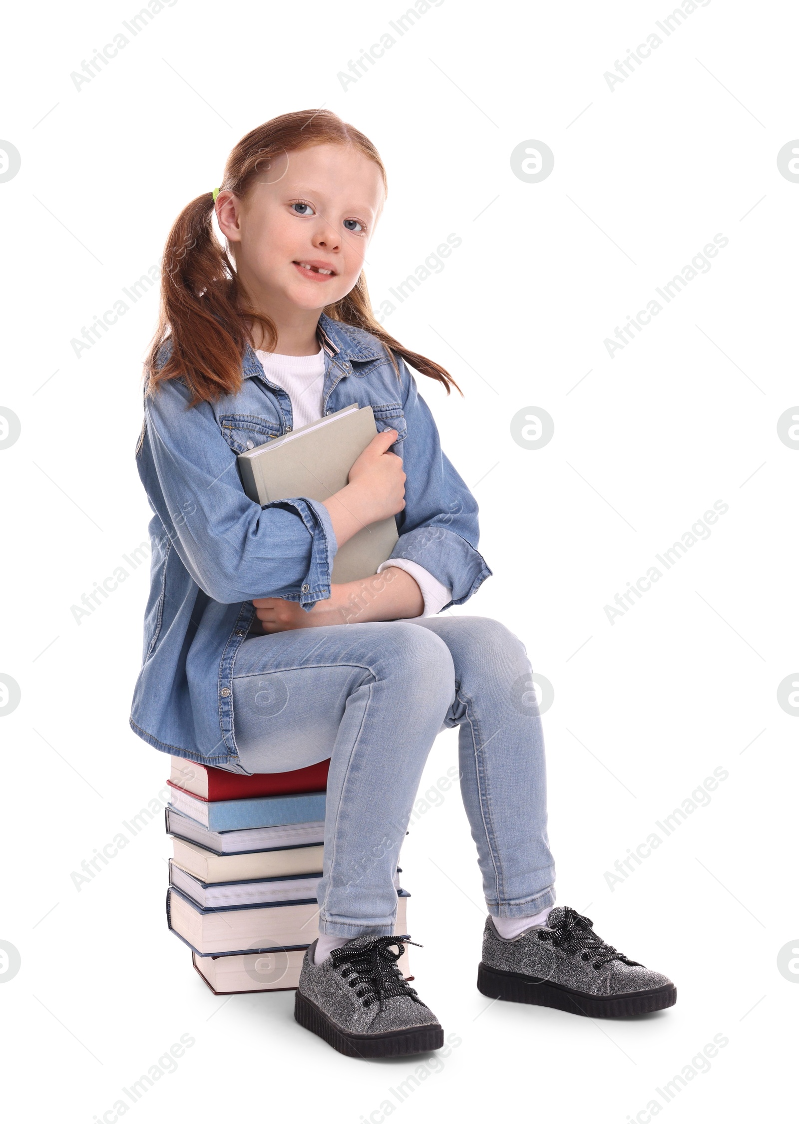 Photo of Smiling little girl sitting on stack of books against white background