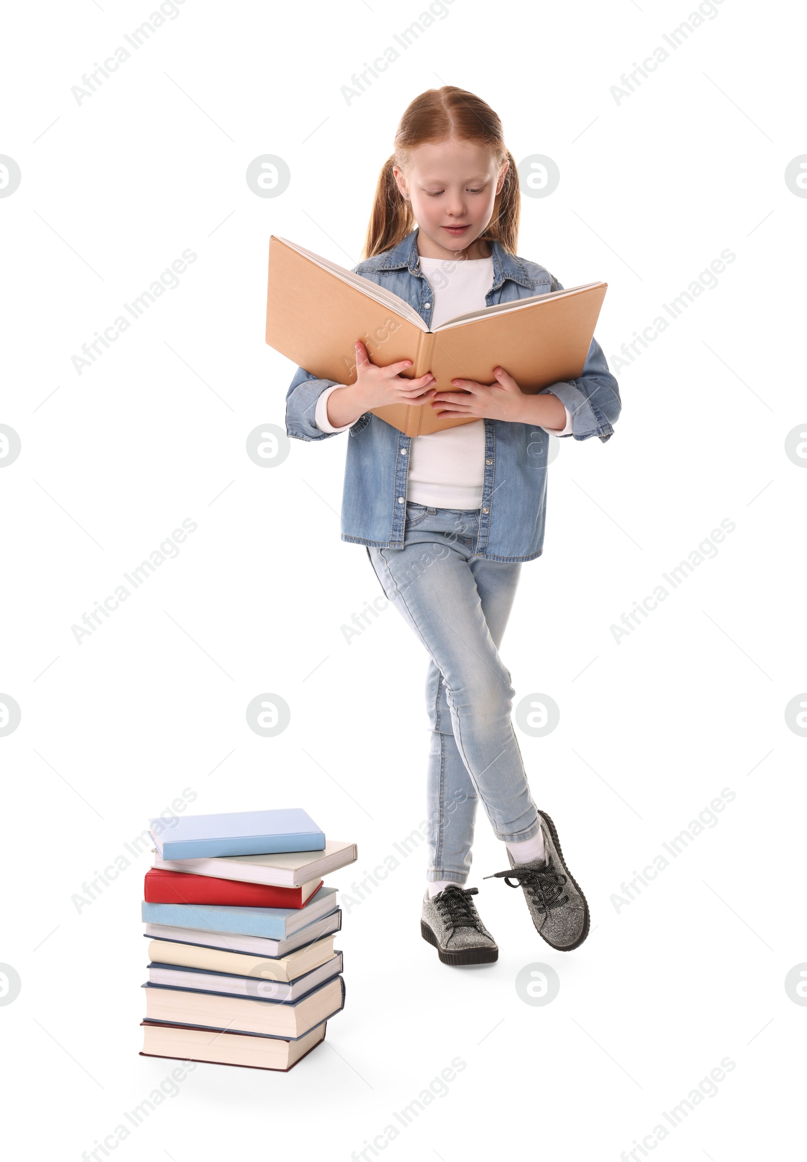 Photo of Cute girl reading near stack of books on white background