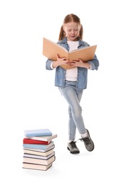 Cute girl reading near stack of books on white background