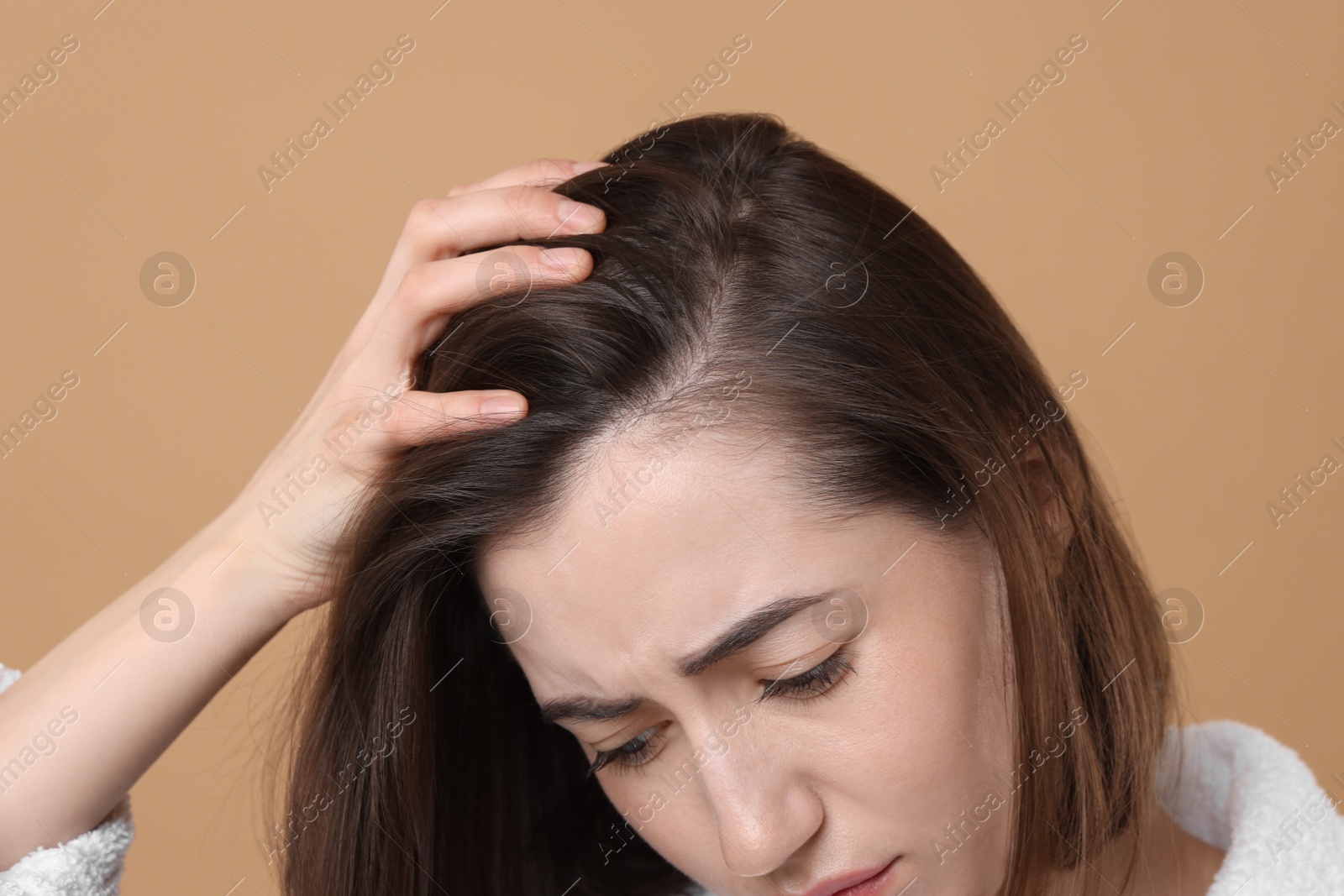 Photo of Sad woman with hair loss problem on light brown background, closeup