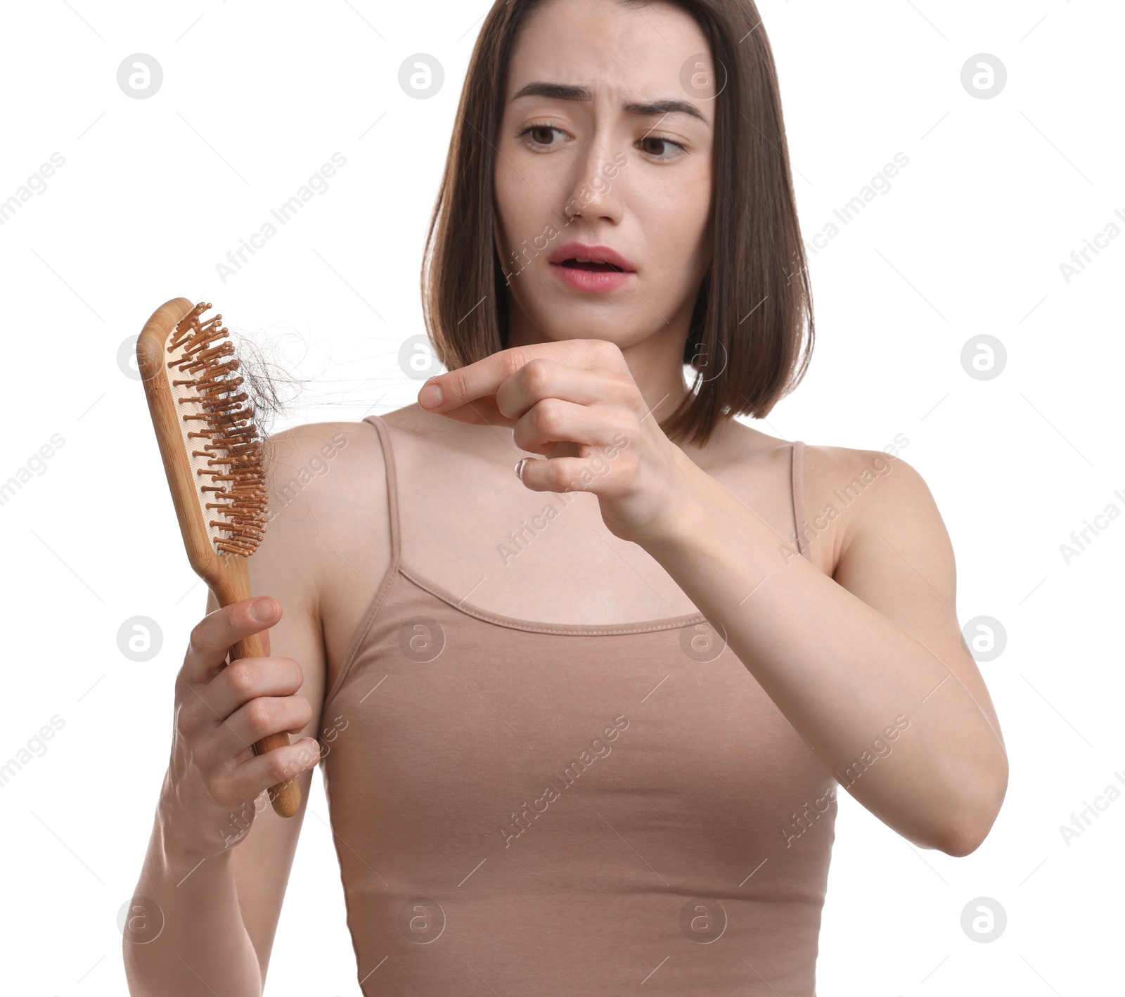 Photo of Stressed woman taking her lost hair from brush on white background. Alopecia problem