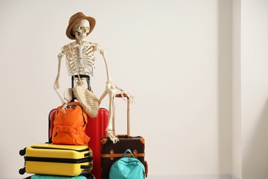 Waiting concept. Human skeleton in hat with suitcases indoors, space for text