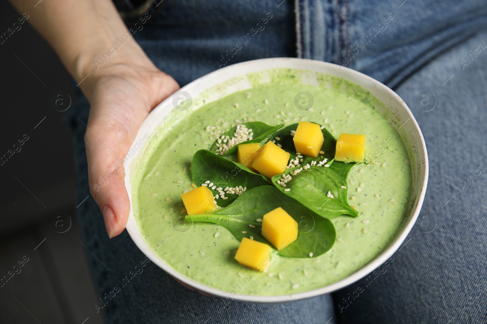 Photo of Woman holding bowl of delicious spinach cream soup, closeup