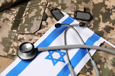 Photo of Stethoscope, flag of Israel, tags and military uniform on table, closeup