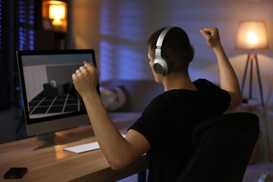 Photo of Man playing video games on computer at table indoors