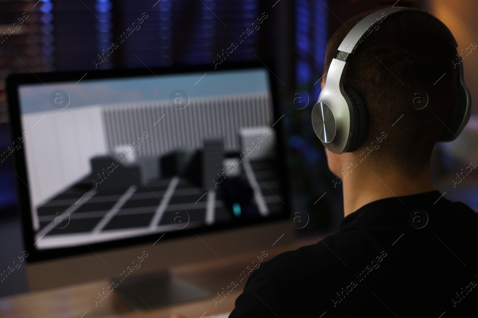 Photo of Man playing video games on computer at table indoors