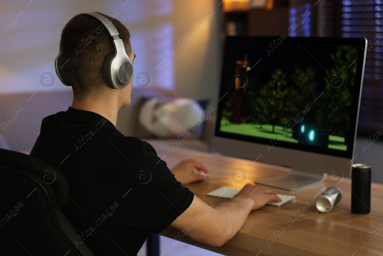 Photo of Man playing video games on computer at table indoors