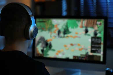 Photo of Man playing video games on computer at table indoors