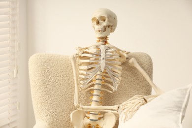 Photo of Waiting concept. Human skeleton sitting in armchair indoors