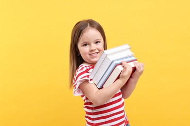 Cute little girl with books against orange background