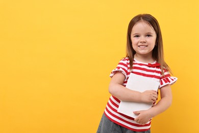 Photo of Cute little girl with book on orange background. Space for text