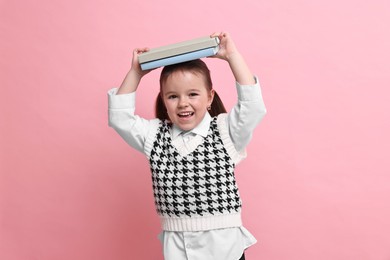 Photo of Cute little girl with books on pink background