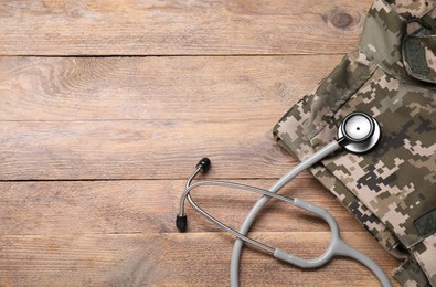 Photo of Stethoscope and military uniform on wooden background, above view. Space for text