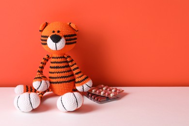 Toy tiger and pills on color background, space for text
