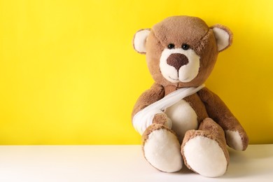 Toy bear with bandage on color background, space for text