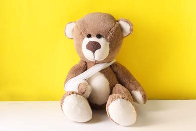 Photo of Toy bear with bandage on color background