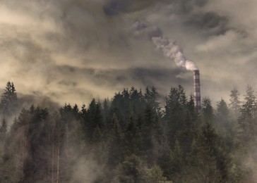 Global warming concept. Factory pipe polluting air near forest