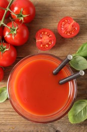 Photo of Tasty tomato juice in glass, basil leaves and fresh vegetables on wooden table, flat lay