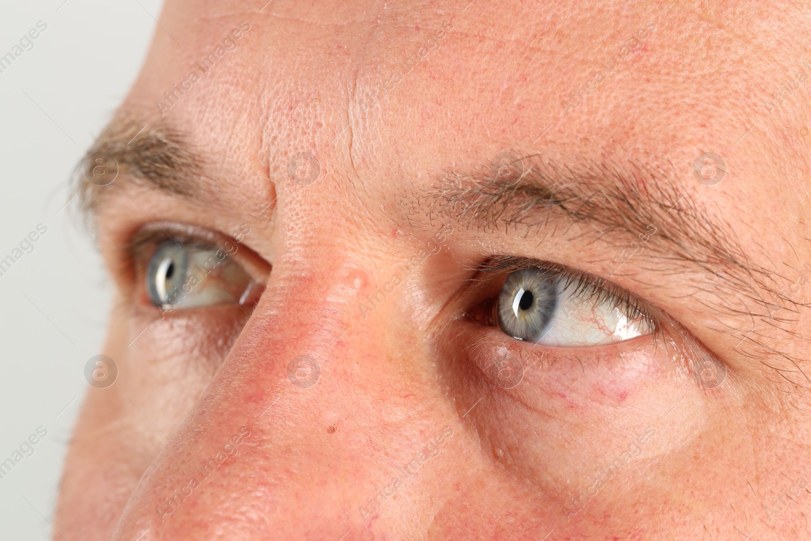 Photo of Man with beautiful blue eyes on light grey background, closeup