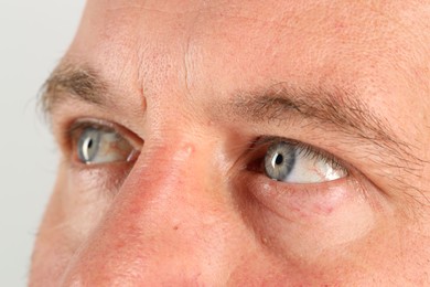 Man with beautiful blue eyes on light grey background, closeup