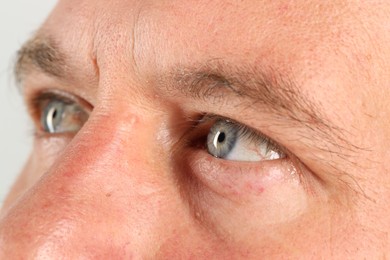 Man with beautiful blue eyes on light grey background, closeup