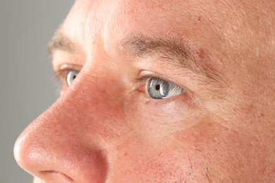 Man with beautiful blue eyes on light grey background, closeup