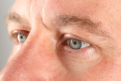 Man with beautiful blue eyes on light grey background, closeup