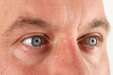 Man with beautiful blue eyes on white background, closeup