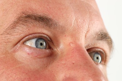 Man with beautiful blue eyes on white background, closeup